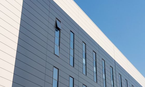 Entrepôt industriel à structure en acier avec porte enroulable et système de bardage en laine de roche ignifuge